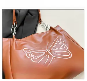 Close-up of brown leather tote bag with elegant 3D butterfly embroidery and chain strap detail