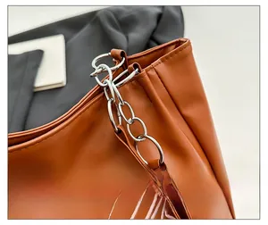 Detail of caramel leather tote with chunky silver chain and pink letter embroidery