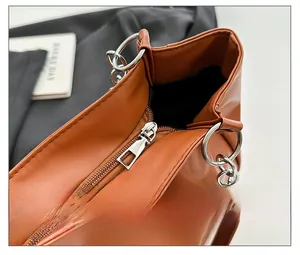 Detail of smooth metal zipper closure and textured brown leather on a large tote bag