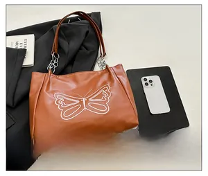 Brown tote bag detail with white butterfly print and silver metal chain strap