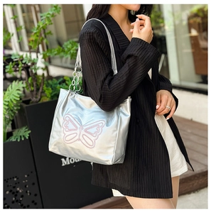 Detail of silver metallic tote bag with pink butterfly embroidery and chain strap detail