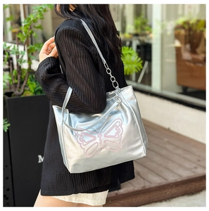 Detail of silver metallic tote bag featuring pink butterfly embroidery and chain strap