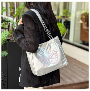 Detail of silver shoulder bag with pink butterfly embroidery and chain strap on model