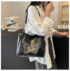 Close-up of black PU leather tote bag with white butterfly embroidery and silver chain detail
