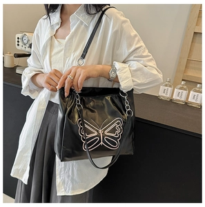 Detail of black leather shoulder bag featuring large pink butterfly embroidery and chain
