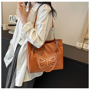 Detail of caramel tote bag with white butterfly embroidery and metal chain strap