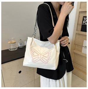 Close-up of a white shoulder bag featuring pink butterfly embroidery and chain strap detail