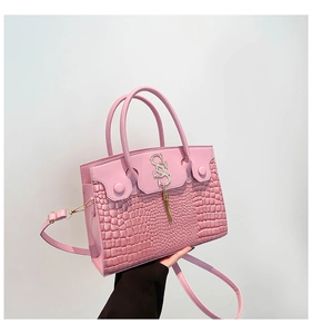 Détail du sac à main rose en cuir croco avec logo métallique et pendentif à franges chic