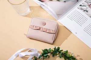 Close-up of light pink leather wallet featuring ruffle lace trim and floral print details