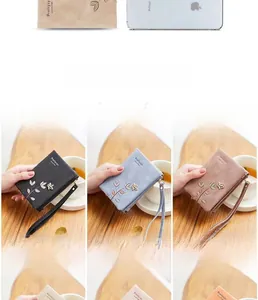 Close-up of floral embroidery on frosted PU leather wallet with zipper detail and wrist strap