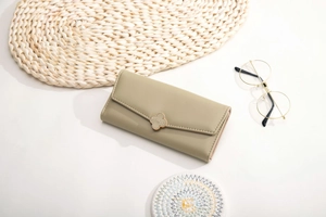 Close-up of green leather long wallet with decorative metal clover buckle and buckle detail