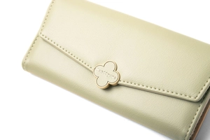 Close-up of a light green leather wallet with a gold clover clasp and Prettyzys logo