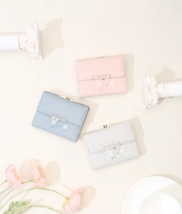 Close-up of three trifold wallets in pink blue and grey with floral prints and metal snap