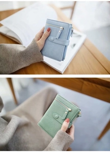 Detail of short leather wallets in light blue and green with zipper and snap button