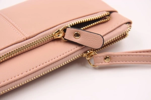 Détail de la fermeture éclair dorée et du cuir grainé sur le portefeuille rose pour femme