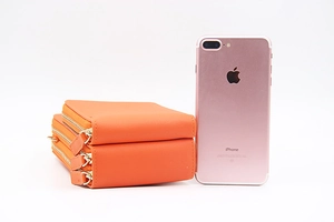 Sac à bandoulière orange à trois fermetures éclair avec un iPhone pour comparer la taille