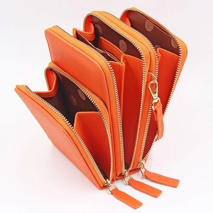 Detail view of the triple zipper compartments and polka dot lining of orange phone bag