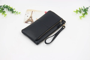 Détail de pochette en cuir PU noir avec trois fermetures dorées et dragonne amovible