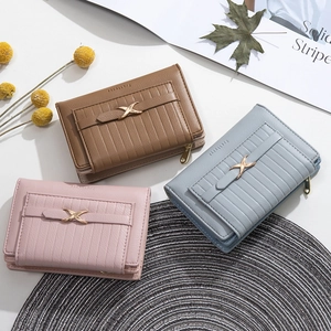 Three minimalist women's short bifold wallets in brown, light blue, and pink with metal buckle