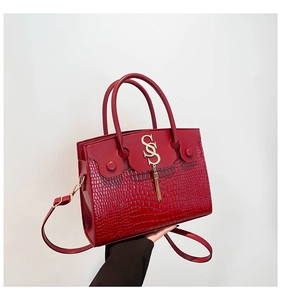 Détail du sac à main rouge motif crocodile avec boucle dorée SGS et pompon à franges