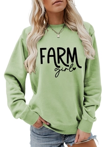 Close-up of light green crewneck sweatshirt featuring black Farm Girl text and ribbed cuffs