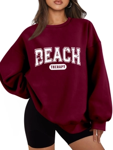 Close-up of Beach Therapy logo and palm tree silhouette on burgundy cotton sweatshirt