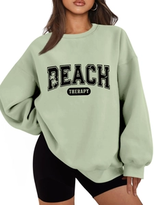 Close-up of mint green crewneck sweatshirt featuring black Beach Therapy graphic print