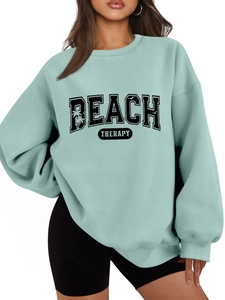 Detail of mint green Beach Therapy sweatshirt with palm tree graphics and oversized fit