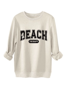 Close-up of BEACH THERAPY text and palm tree graphics on cream crewneck sweatshirt