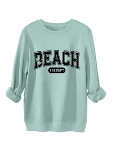 Detailed flat lay of mint green sweatshirt featuring Beach Therapy palm tree graphic