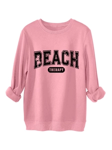 Close-up of pink crewneck sweatshirt featuring black Beach Therapy palm tree graphic