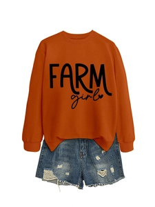 Flat lay of an orange crewneck sweatshirt with 'FARM girl' text and ripped denim shorts