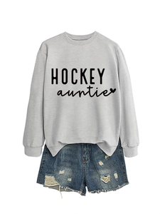 Gros plan du sweat gris Hockey Auntie avec un short en jean usé sur fond blanc épuré et moderne