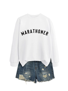 Flat lay of a white crew neck sweatshirt with black Marathoner text and distressed denim shorts