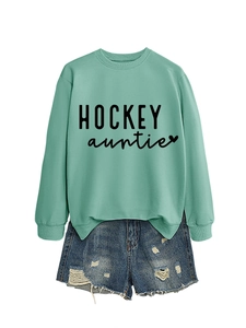 Détail du sweat Hockey Auntie vert clair avec un short en jean bleu délavé usé