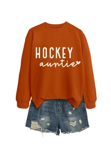 Détail du sweat orange Hockey Auntie avec texte blanc et short en jean vieilli