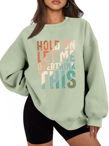 Detail of artistic 'Hold On Let Me Overthink' colorful text print on green sweatshirt