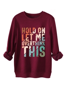Detail of the oversized text print with retro striped pattern on a burgundy sweatshirt