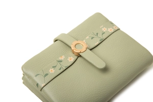 Detail of light green leather wallet with daisy floral print and golden round buckle clasp
