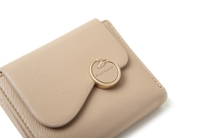 Close-up of golden round metal clasp on beige litchi pattern folding wallet