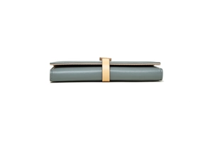 Side view detail of a slim grey-blue tri-fold leather wallet with apricot strap