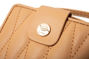 Detailed close-up of beige leaf-shaped metal buckle on quilted pebbled leather wallet