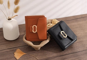 Litchi pattern leather wallets in brown and black on wood with leaf shadows