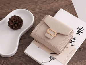 Close-up of beige PU leather wallet featuring pebble texture and gold metal logo buckle