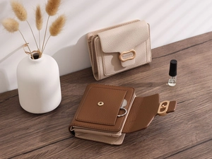 Detail view of leather wallets with gold metal clasps on a rustic wooden table