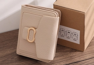 Detail of lychee textured PU leather wallet with a golden metal buckle on wood background