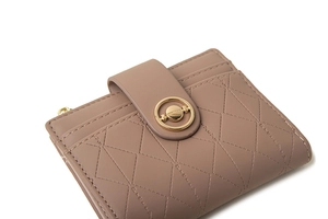 Detailed view of quilted faux leather wallet with gold ring buckle and elegant stitching