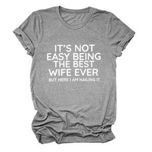 Vista piatta della t-shirt grigia con lo slogan It's Not Easy Being The Best Wife Ever e tessuto