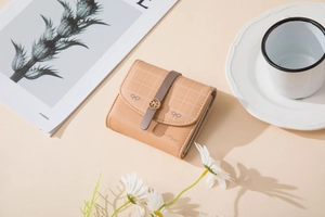 Detail of light beige PU leather trifold wallet with checkered flap and bow buckle