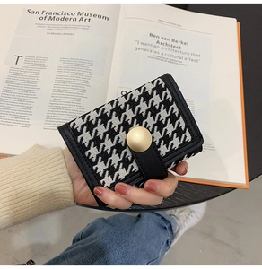 Close-up of houndstooth wallet featuring a golden snap button on SFMOMA art book